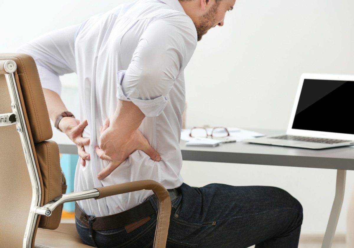 Young man suffering from backache in office, closeup