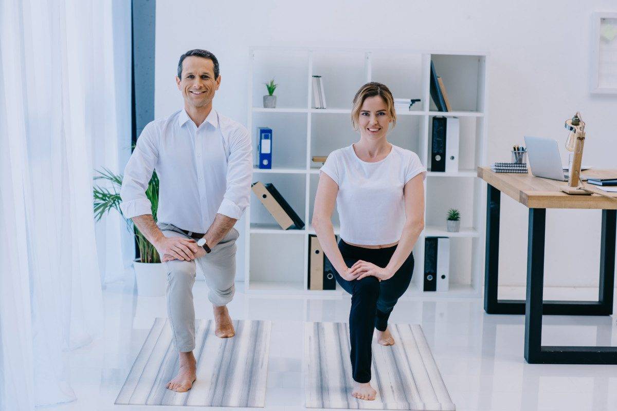 businessman with his trainer practicing yoga in Crescent Lunge pose at office