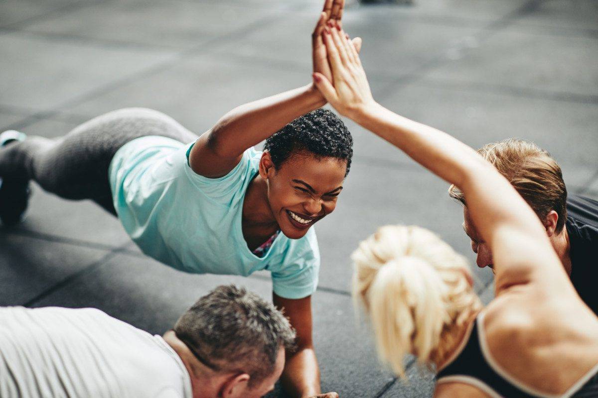 Laughing women high fiving while planking in a gym class