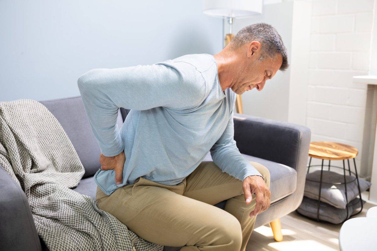 Man On Sofa Suffering From Backache