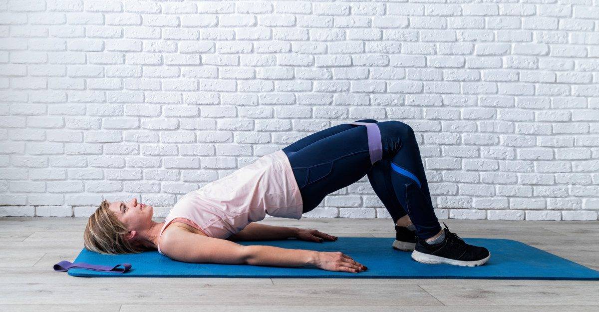 Woman doing exercise for glute hip bridge abduction using rubber resistance band