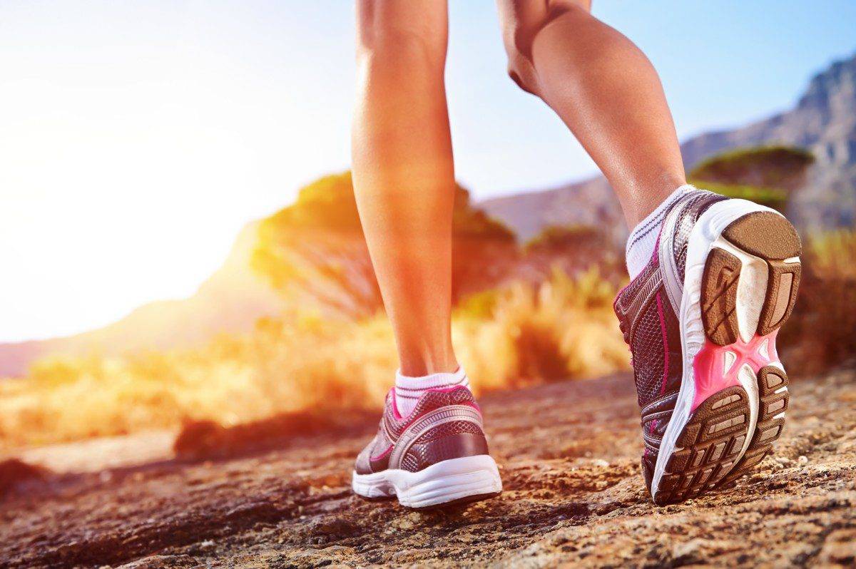 a woman is running on a trail in the sun